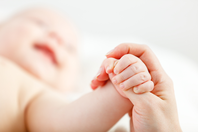 concept of parental love. newborn baby hand holding  finger of mother